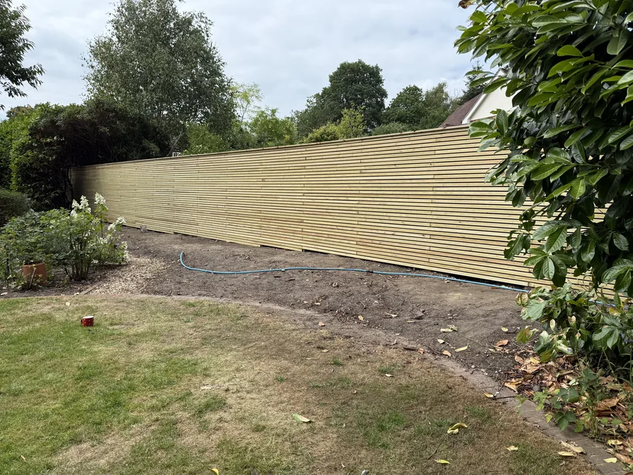 Long completed run of green timber slatted boundary fencing