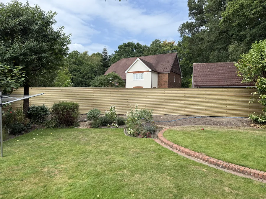 Finished slatted fence following the garden boundary across uneven ground