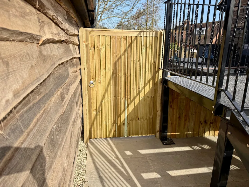 Timber side gate beside a raised metal walkway